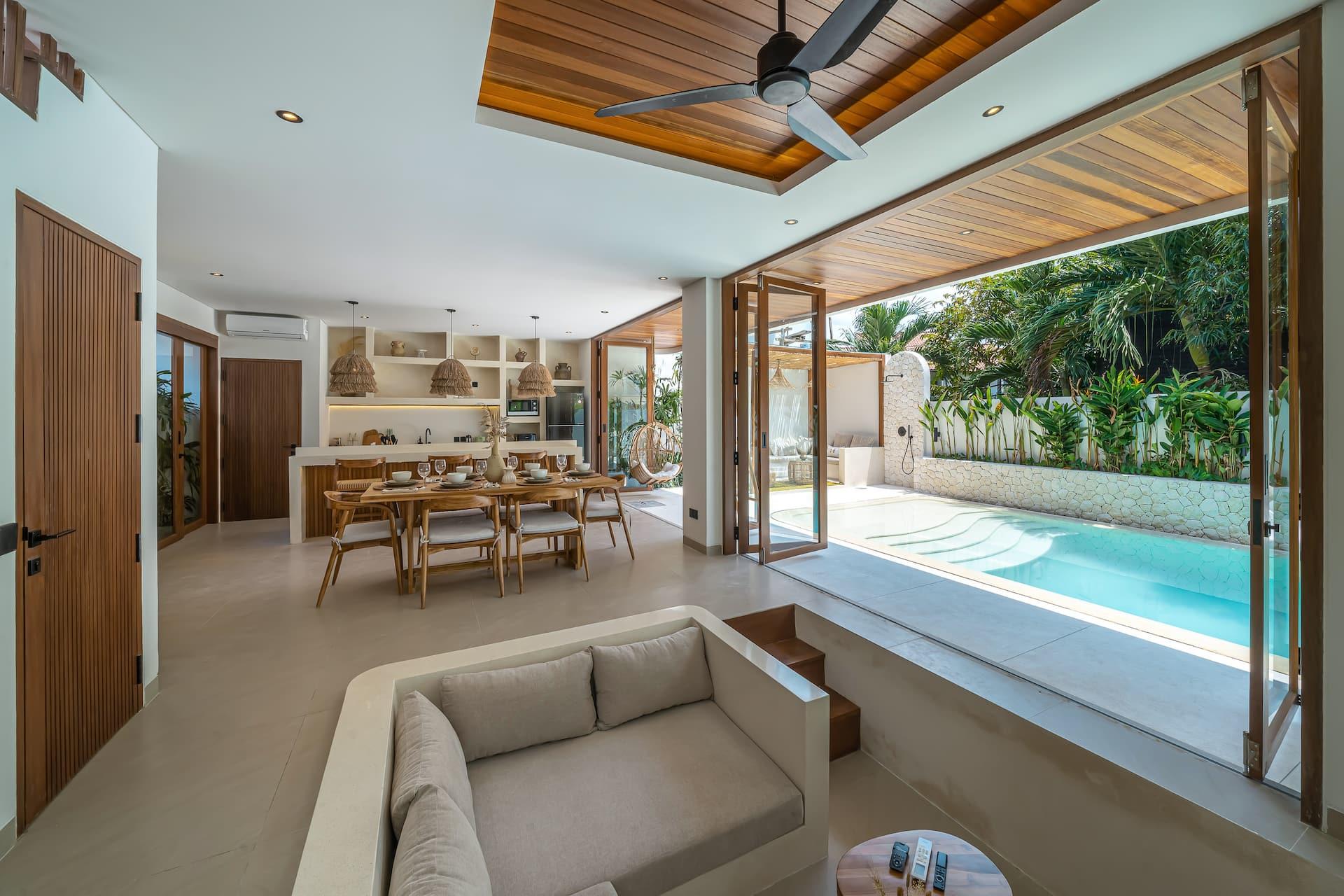 Living room, dining table and kitchen run as one long room down the side of the pool at Villa Paraiso