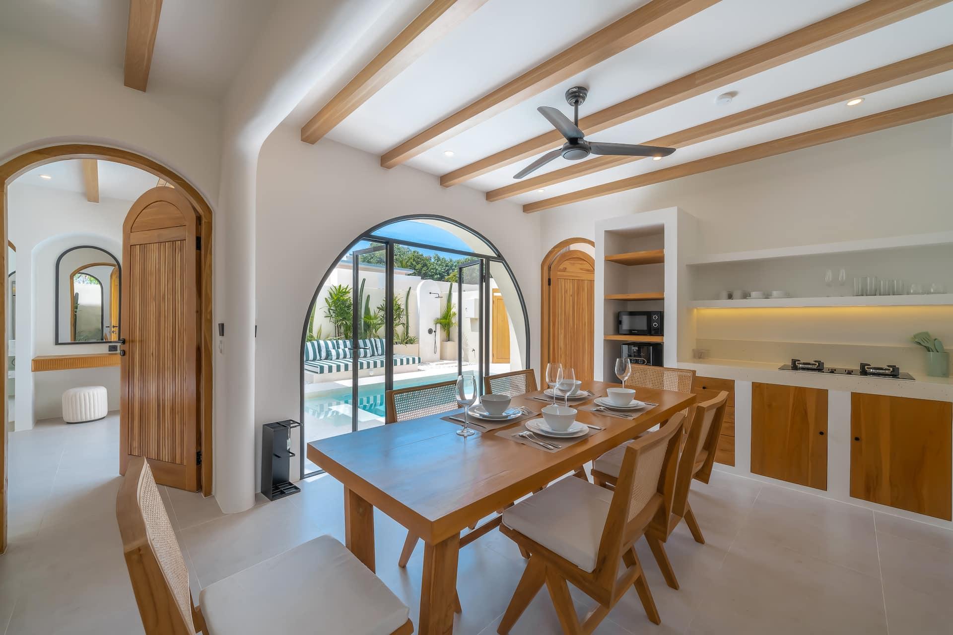 Chandigarh-style chairs around the oak table, the kitchen and its arched niche behind