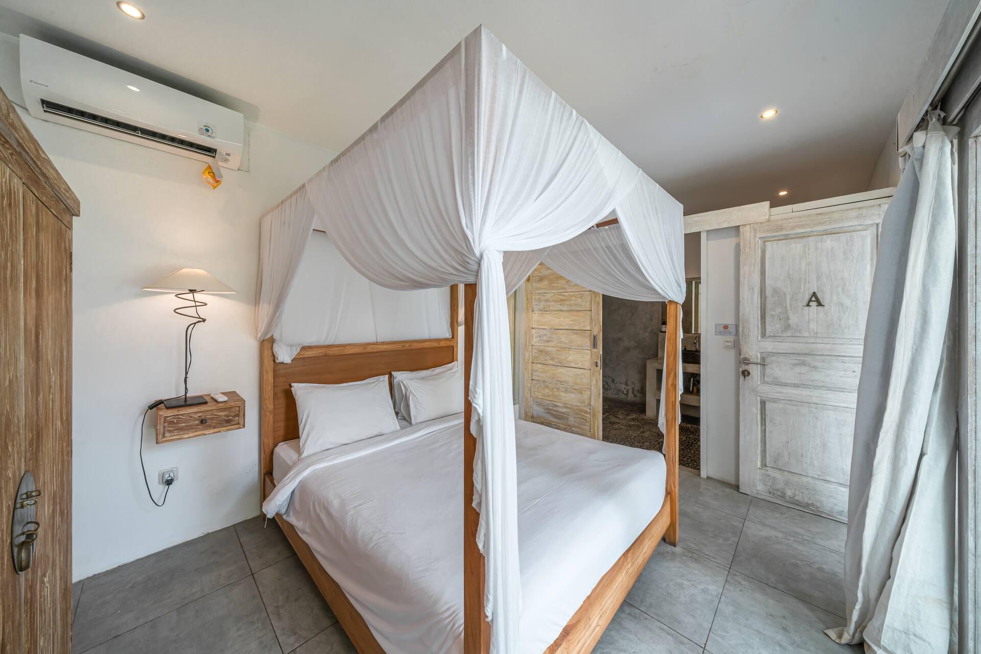 Bedroom at Villa Palm Tree with a canopied four-poster and tall reclaimed timber doors