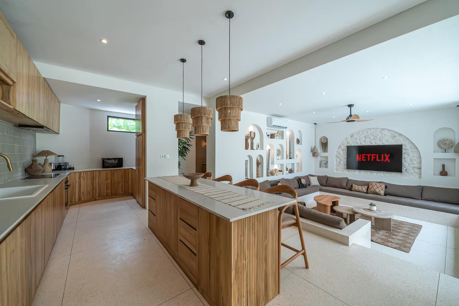 Kitchen island in stone and timber with rattan bar stools, open to the lounge at Casa Amici 8