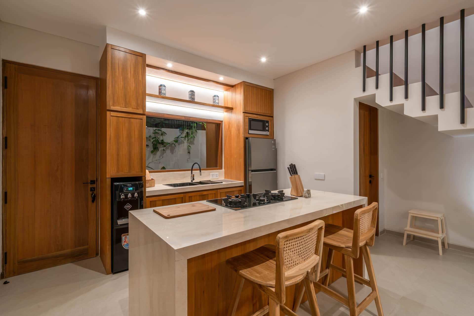 Kitchen at Villa LouLou with a stone island, woven bar stools, gas hob and built-in oven