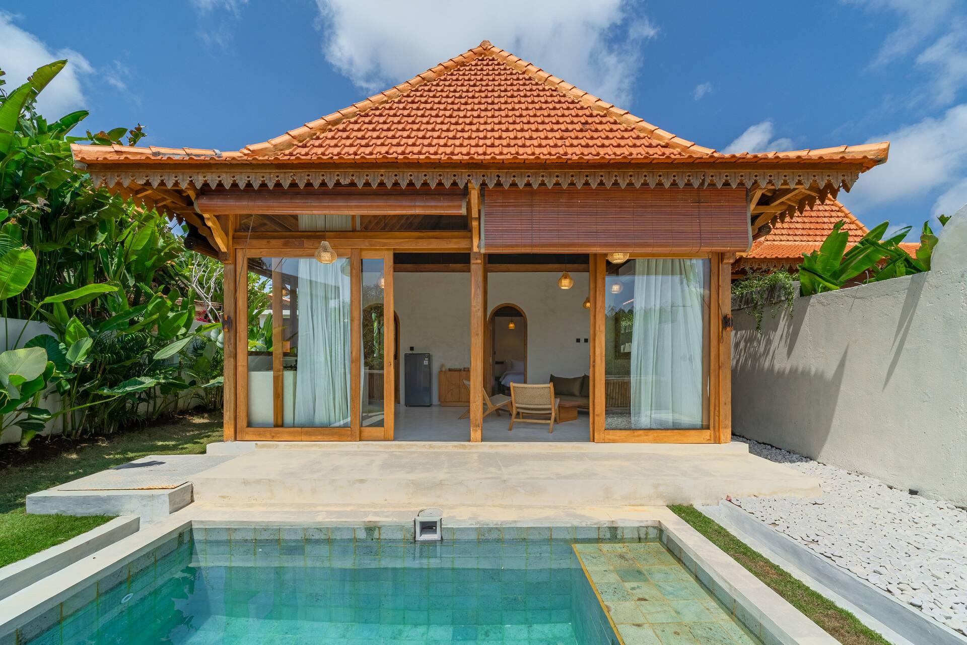 Rumah Tirta's joglo-style pavilion with terracotta roof and glass doors facing the private pool