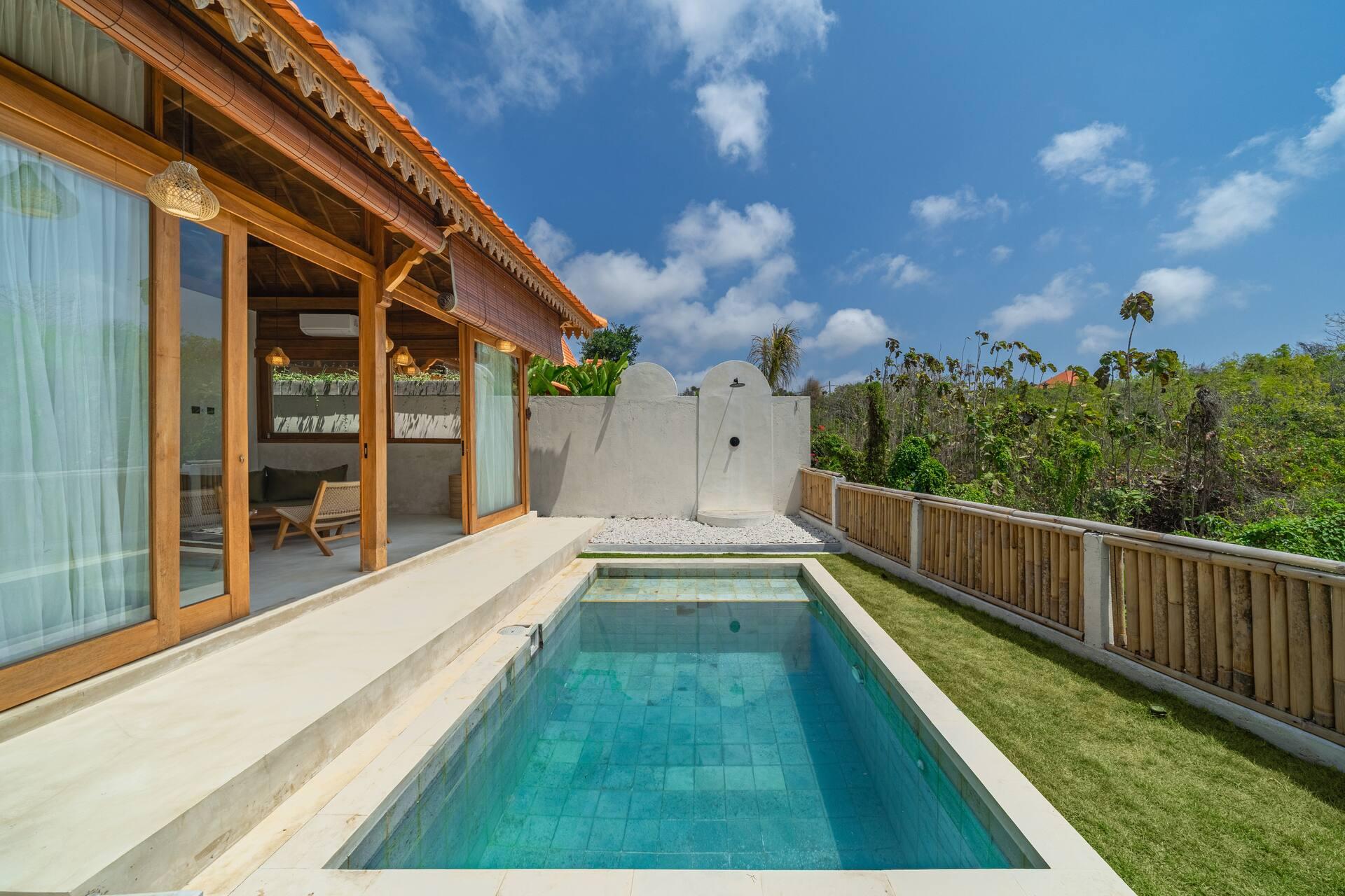 Rectangular plunge pool in a lawned garden with timber fencing and the pavilion beside it