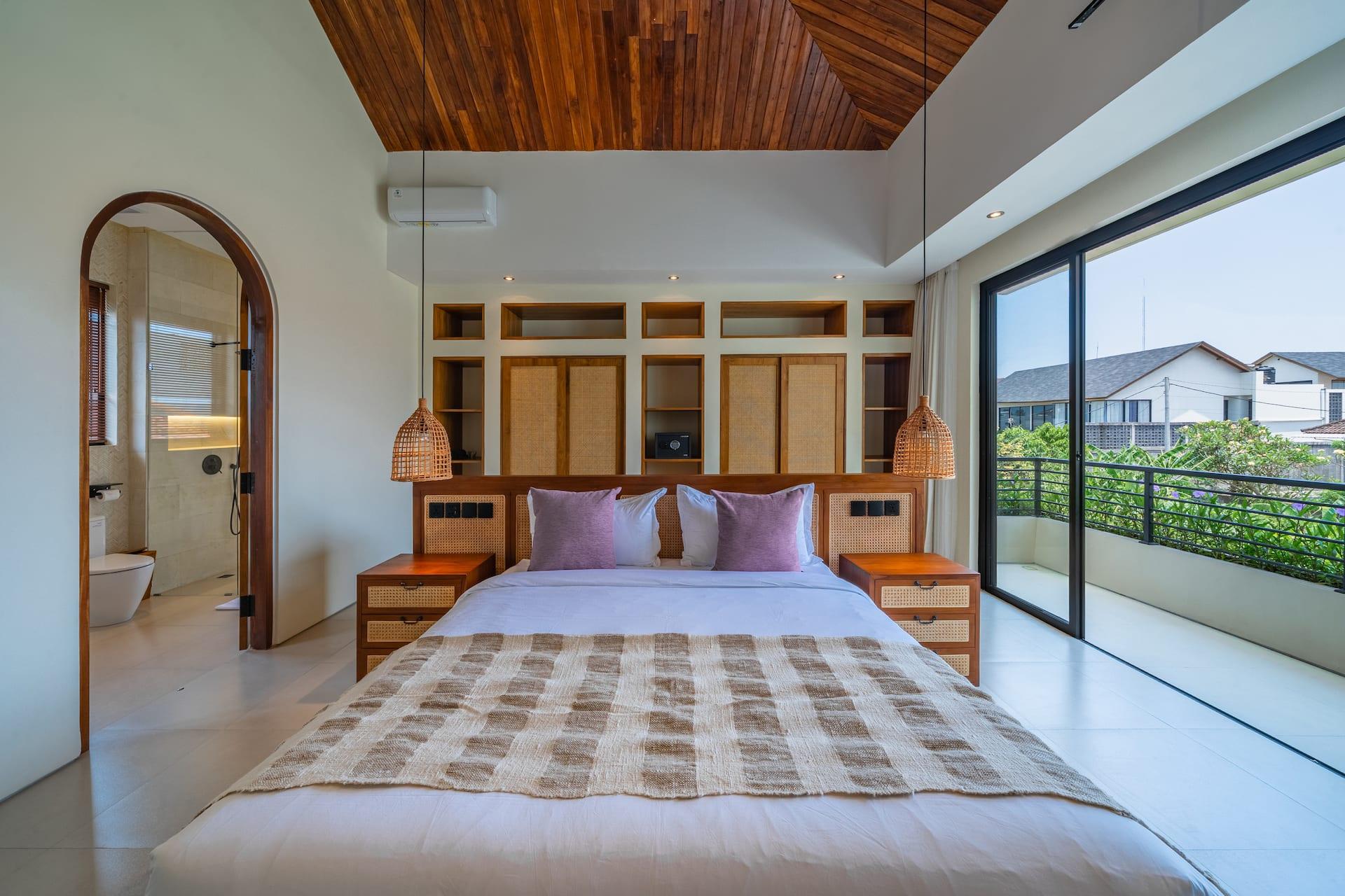 Upstairs bedroom under a pitched timber ceiling with sliding glass doors to a private balcony