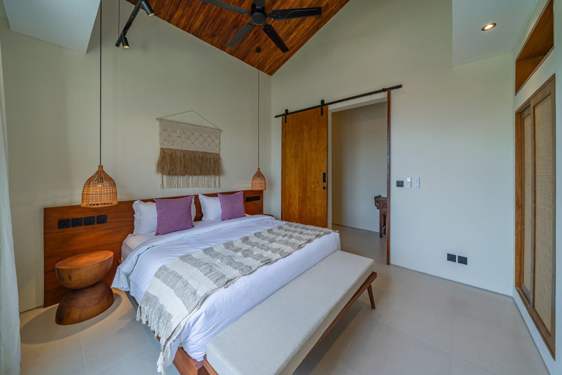 Bedroom with a sliding timber barn door, macramé wall hanging and pitched timber ceiling