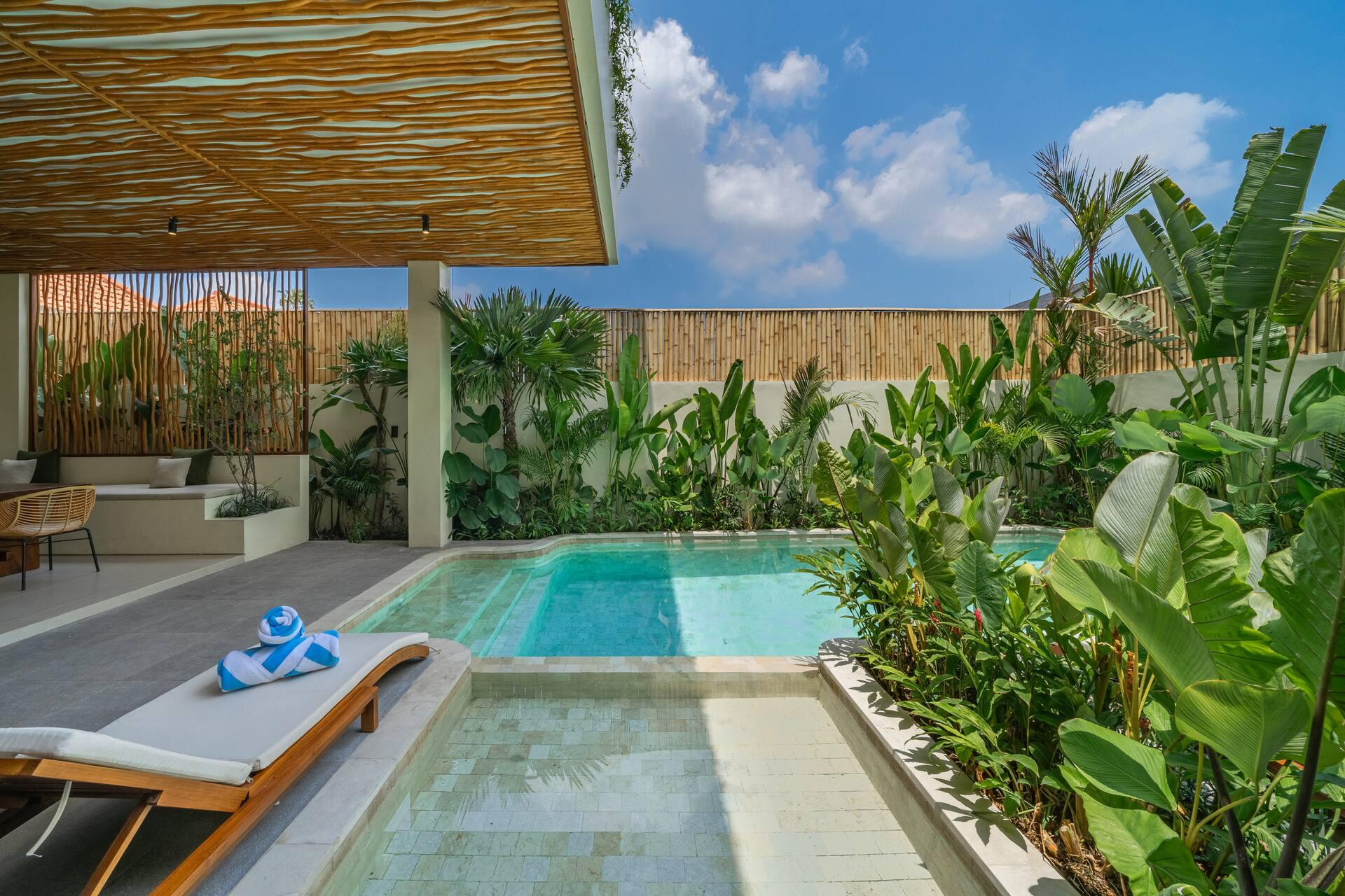 Shallow tiled lounging shelf at the end of the pool with a sun lounger and folded towels