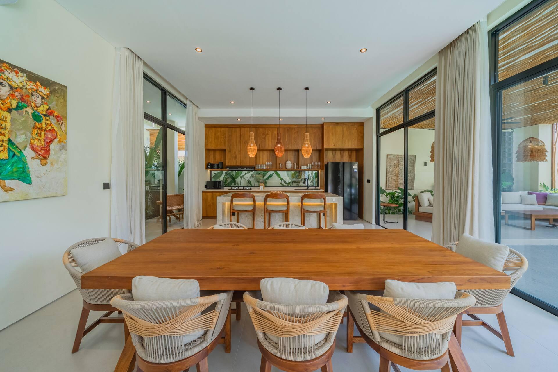 Dining table for eight with woven chairs, set between the timber kitchen and the garden windows