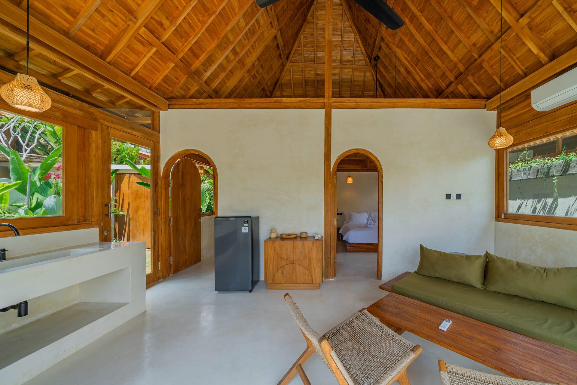 Open-plan interior with a green-cushioned daybed, timber coffee table and arched doorways