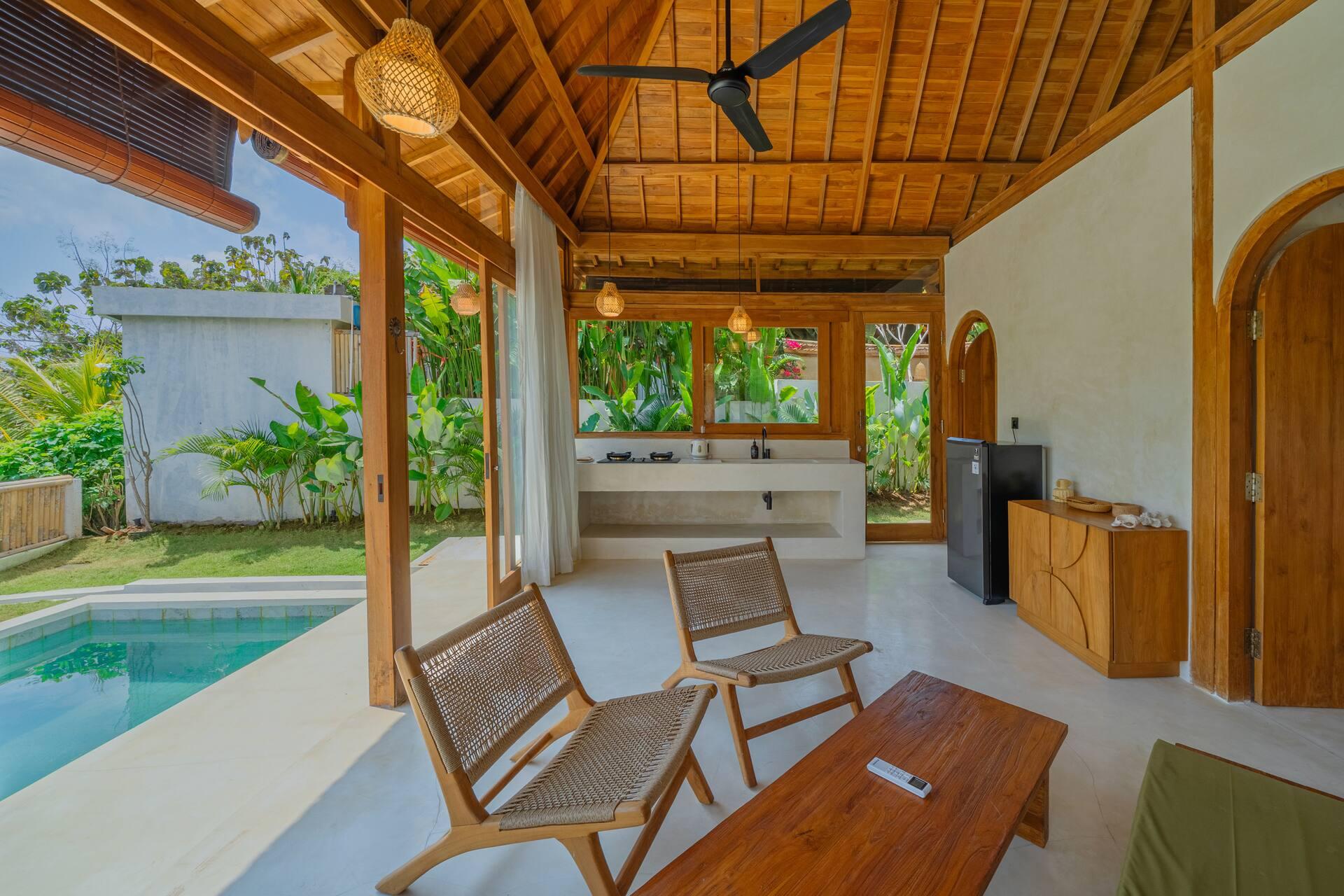 Lounge chairs and coffee table in the living pavilion with the pool visible through the doors