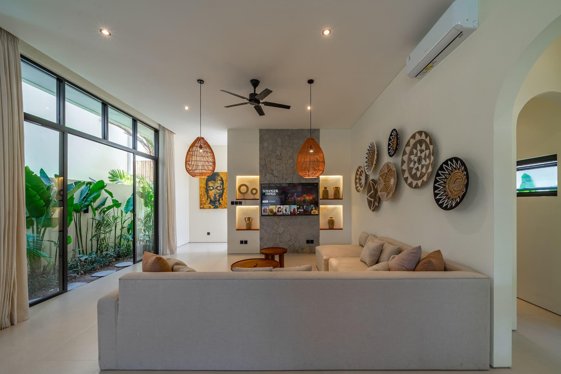 Villa Hanua living room seen from the stairs, with woven wall plates and rattan pendant lights