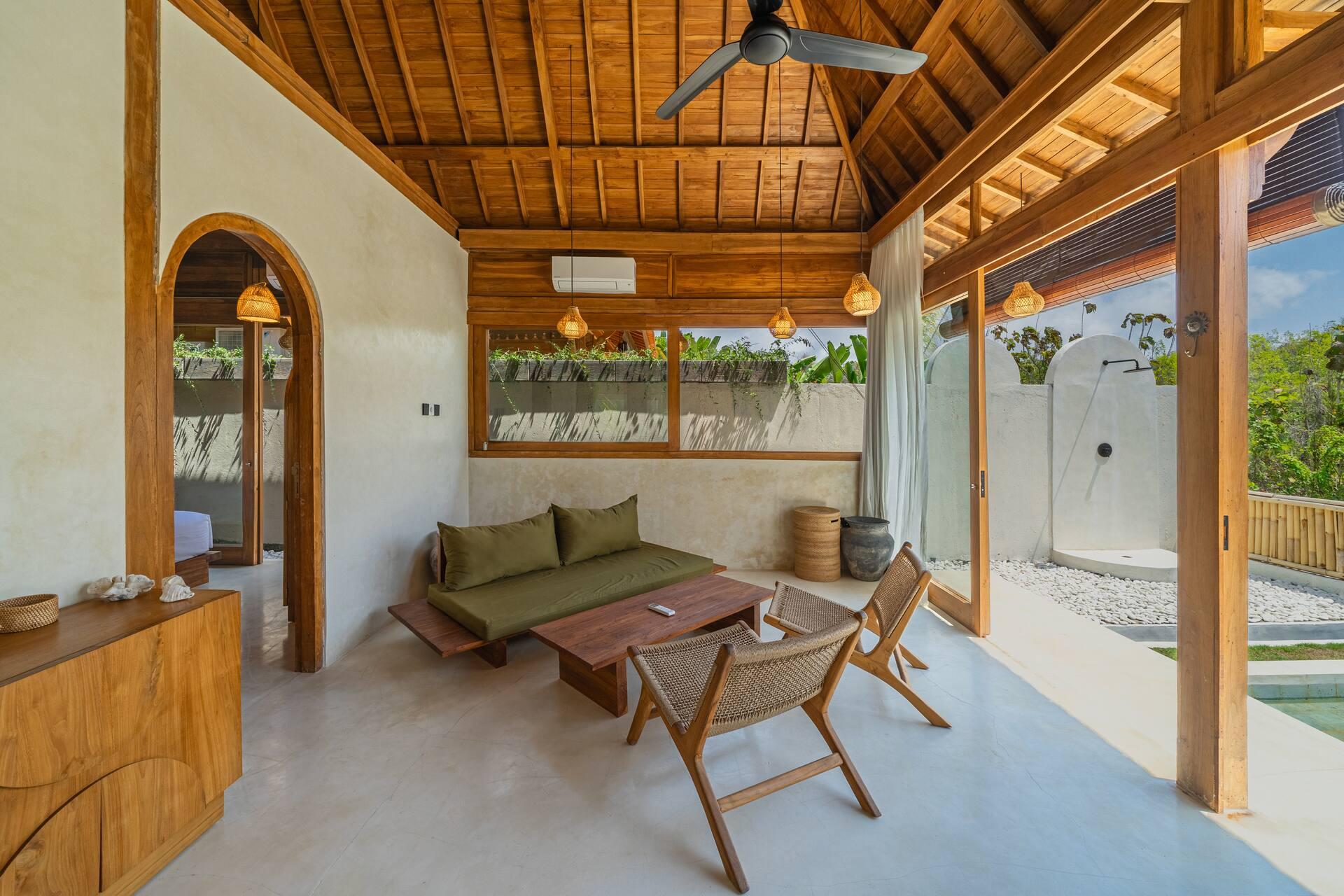 Living space at Rumah Tirta with arched door, kitchenette counter and rattan pendant lights