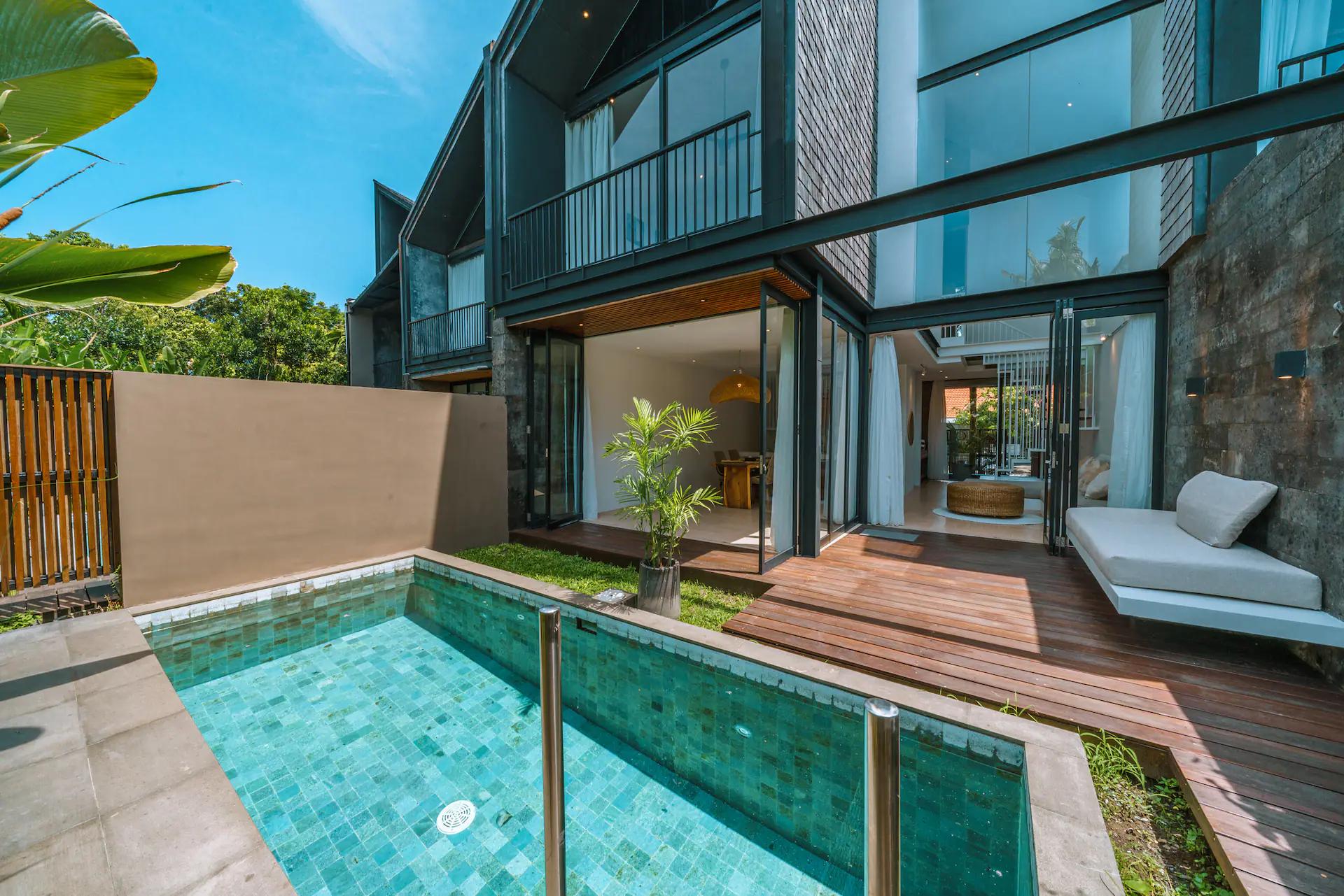 The emerald-tiled lap pool at Villa RIZR, hardwood deck and dark timber-clad house behind