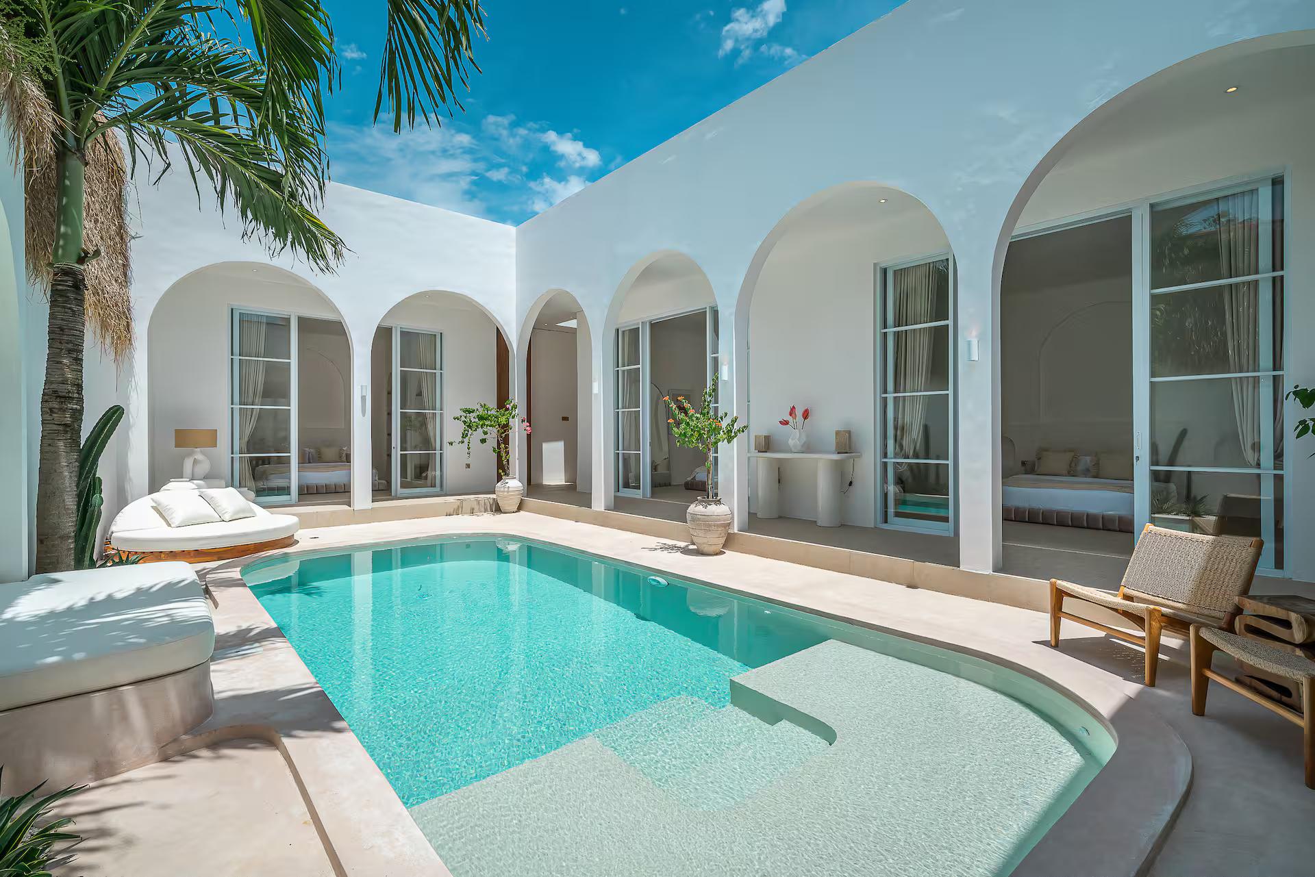 The free-form pool at Villa Halo, held between an arcade of white arches and the palms