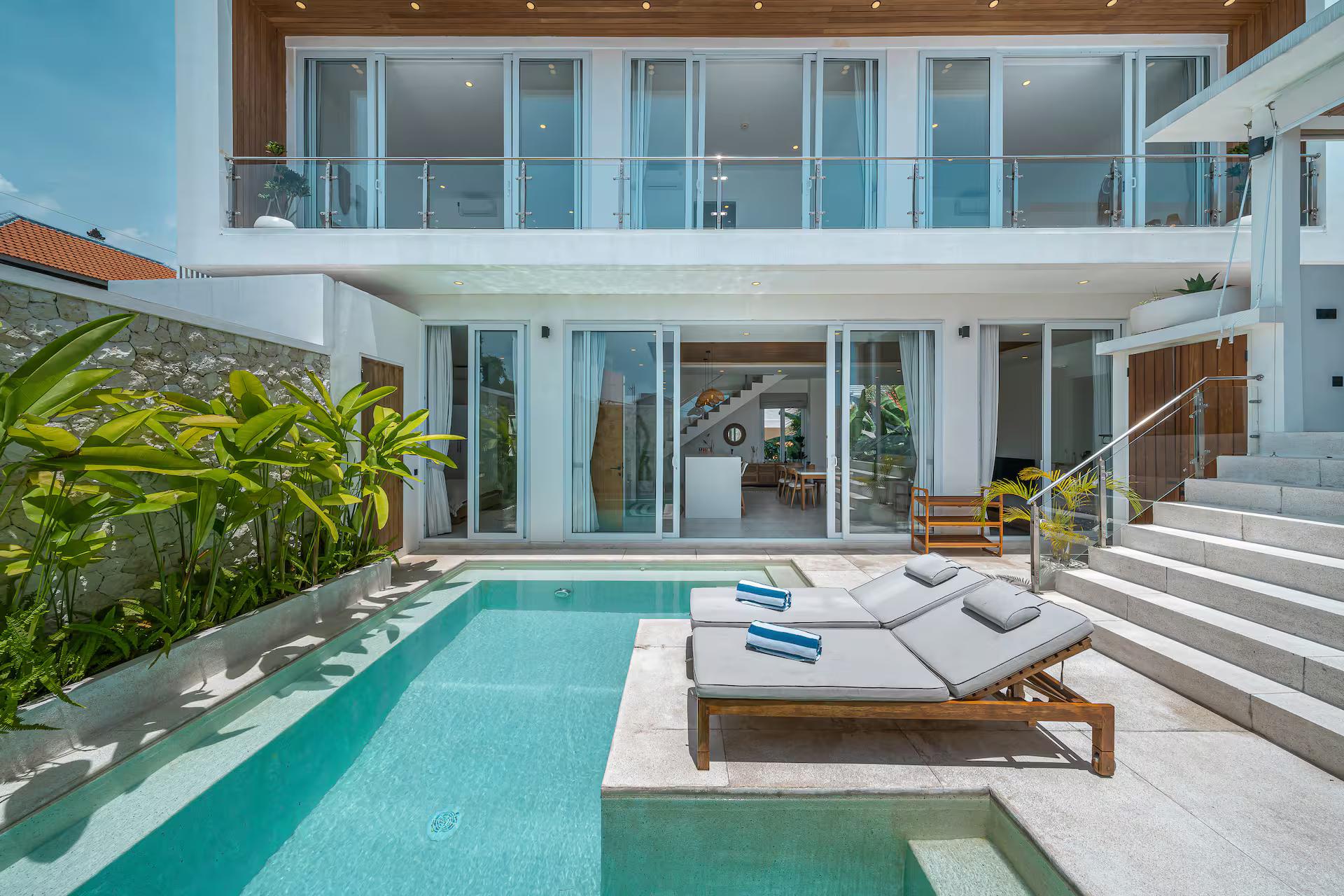 The pool at Villa Era with its raised stone sun platform, the three-storey house behind