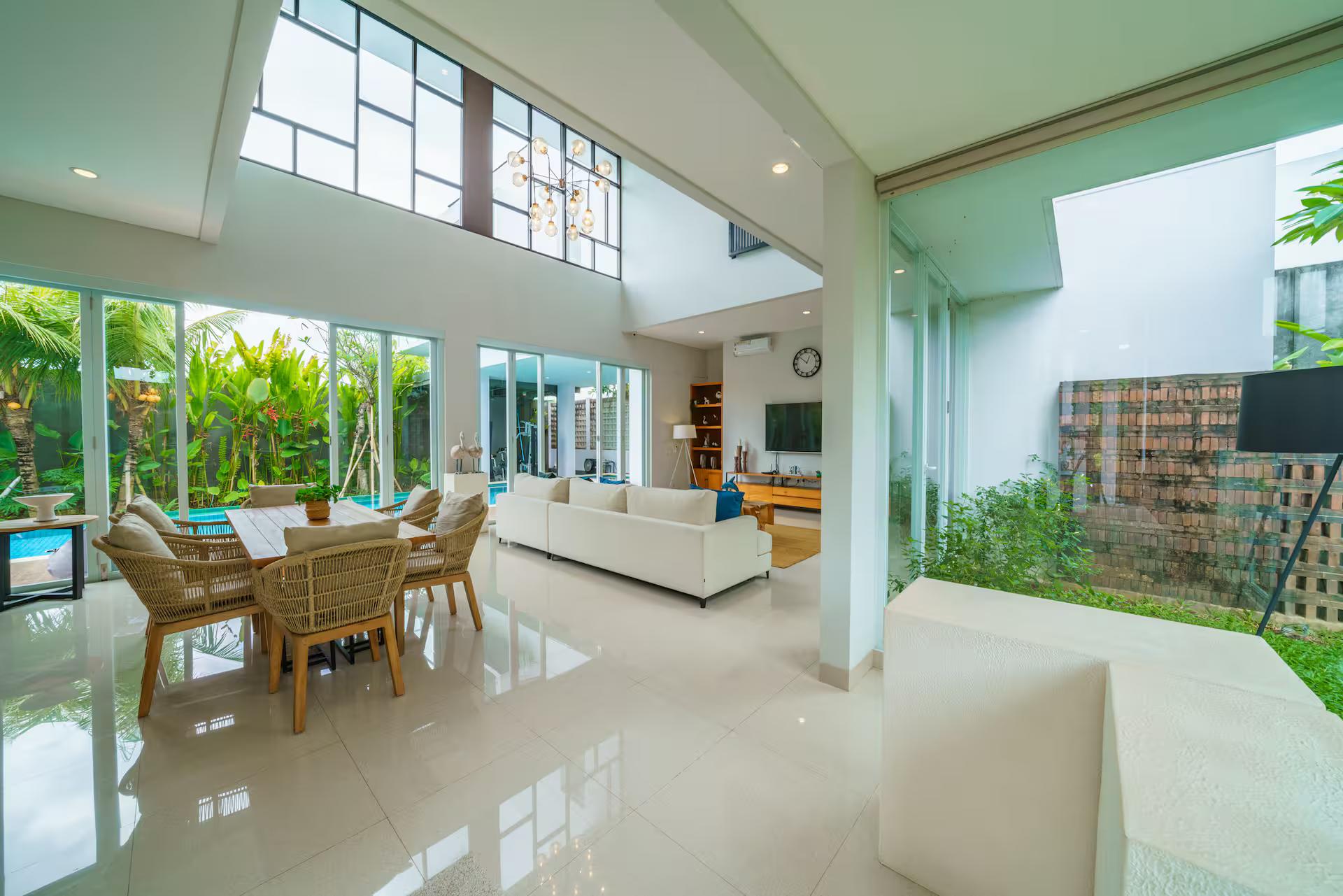 Covered terrace at Villa Ammanya with rattan armchairs, open to the lap pool and lawn