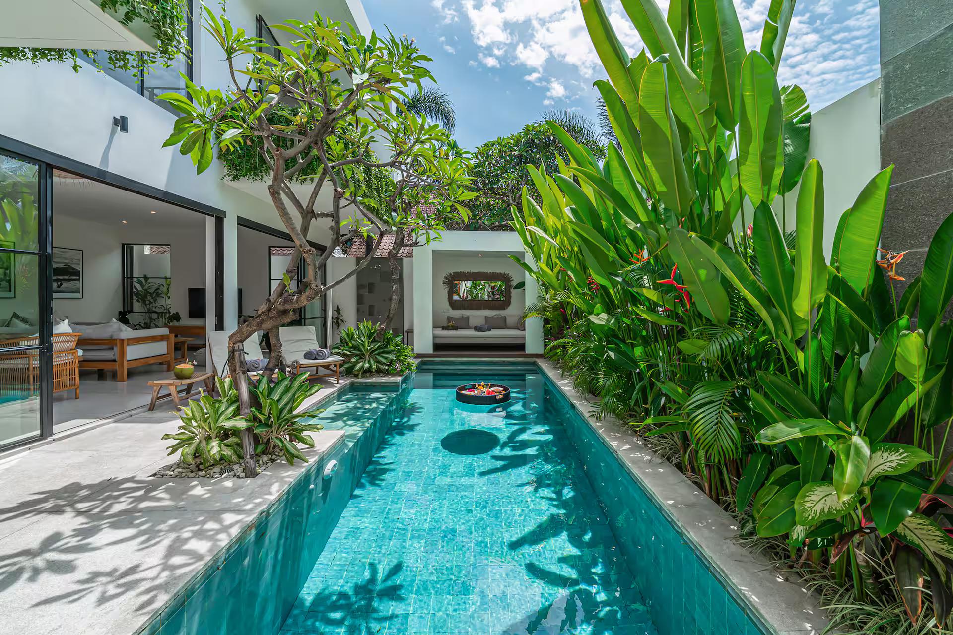 The turquoise lap pool at Villa Puri Senang, shaded by a frangipani and walled in heliconia