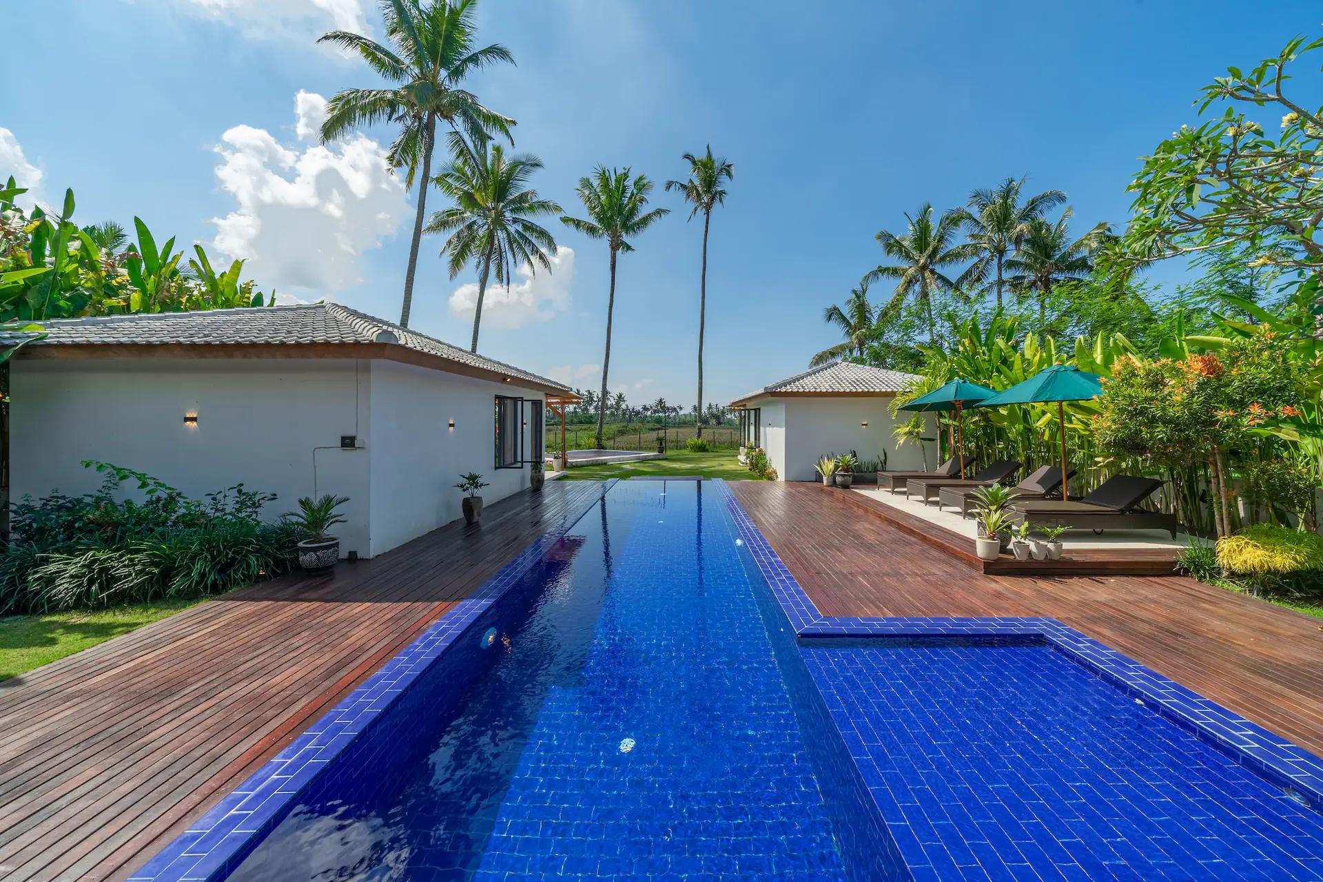 The cobalt-tiled pool at Villa Wellness Bisous with its ipe timber deck and coconut palms behind