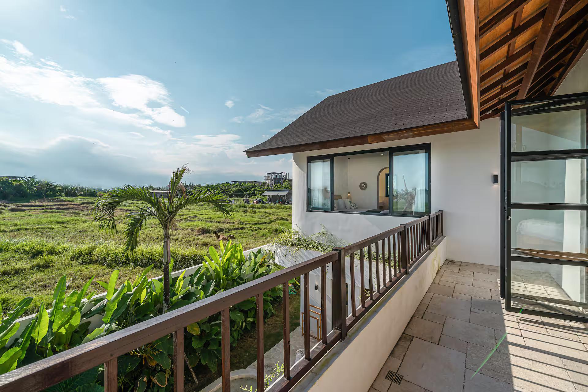 First-floor walkway with a timber balustrade looking out over open rice fields at Sunbeam Oasis