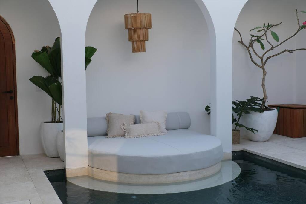 A round built-in daybed set into the edge of the pool between two white plaster arches