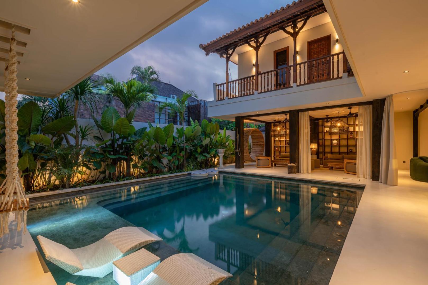 Sun loungers at the pool edge with the first-floor timber gallery running overhead