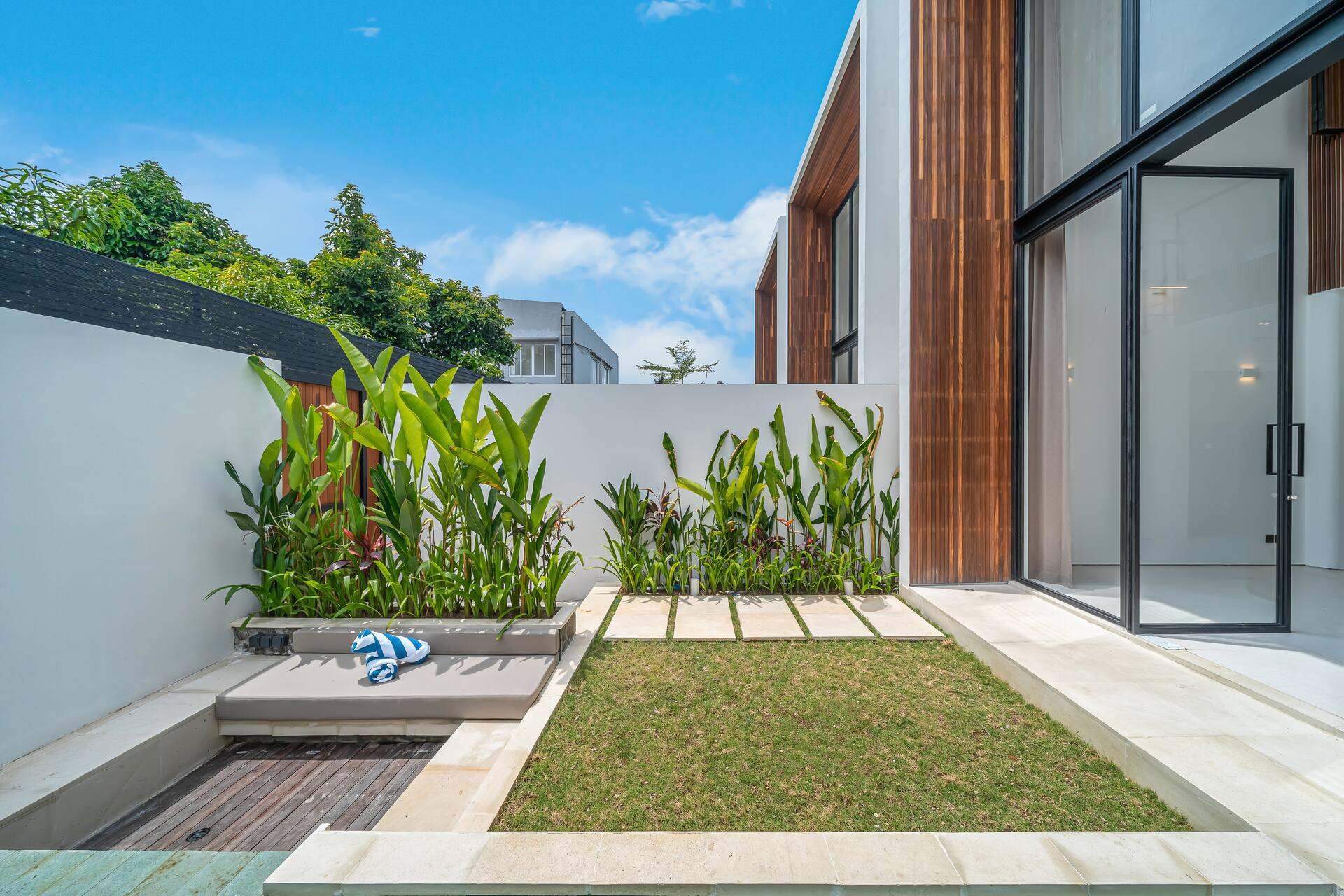 Timber sun deck and lawn strip running beside the long private pool at Fire Villa Berawa