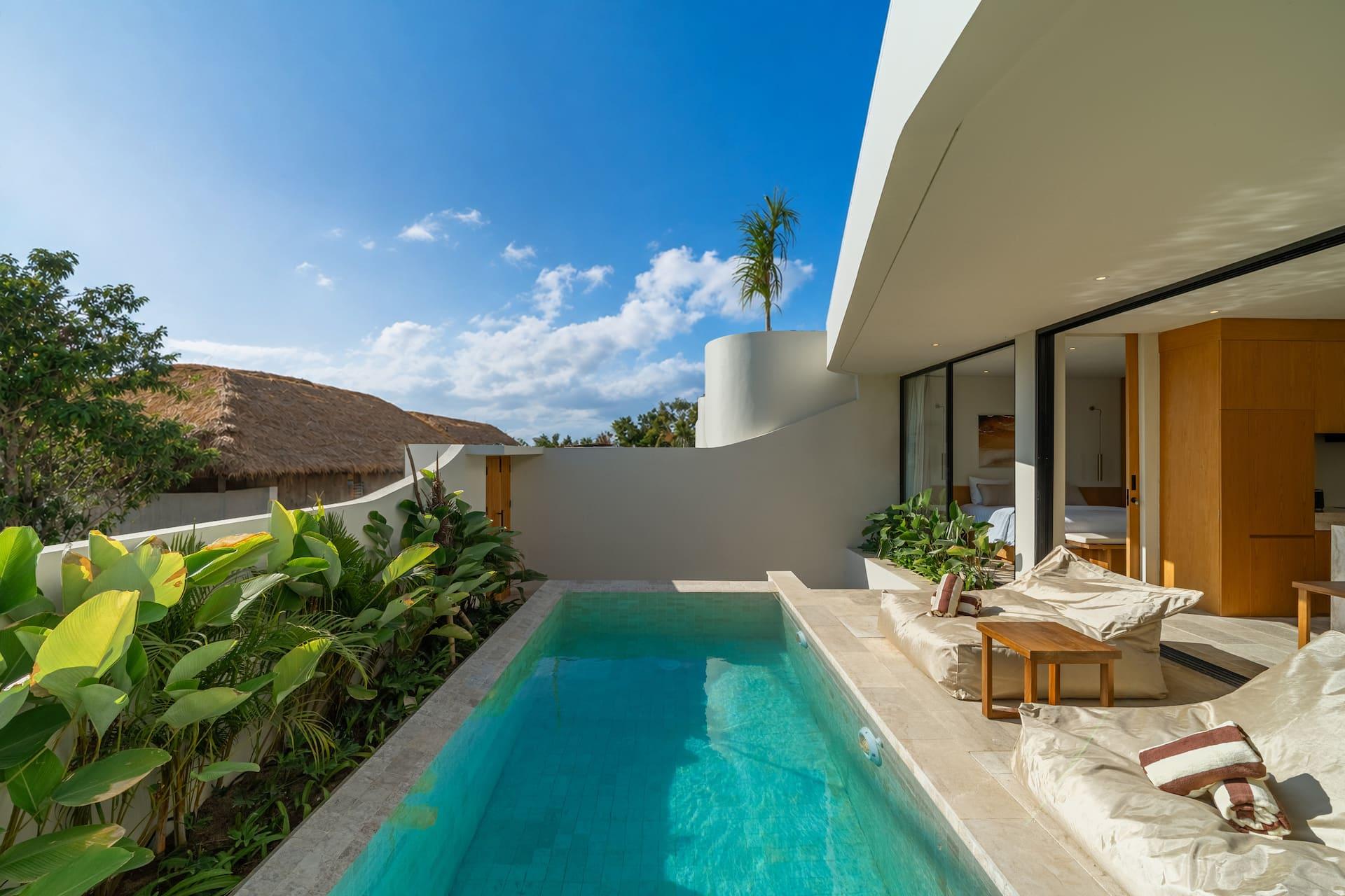 The pool at Villa Amber with banana palms along one edge and the Bukit's dry hills on the horizon