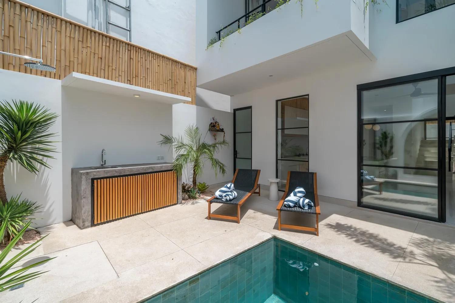 An outdoor rain shower and concrete counter beside the pool, screened in split bamboo