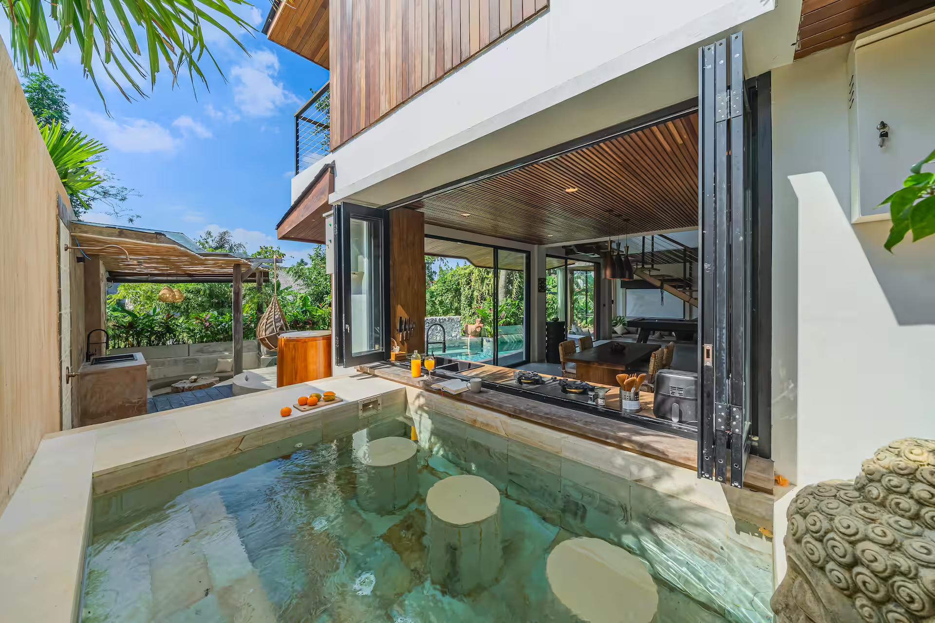 Three stone stools stand in the water at the swim-up counter at The Banyan Pererenan