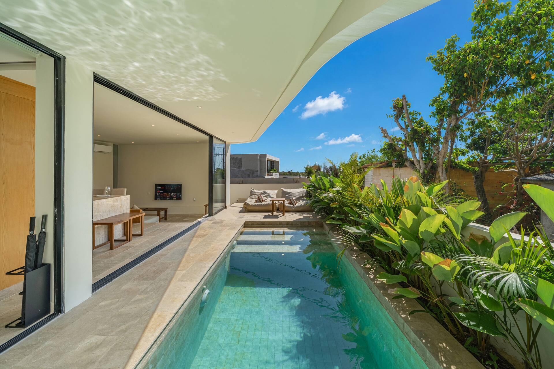 Turquoise pool at Villa Aura edged with banana palms and traveller's palms in Bingin