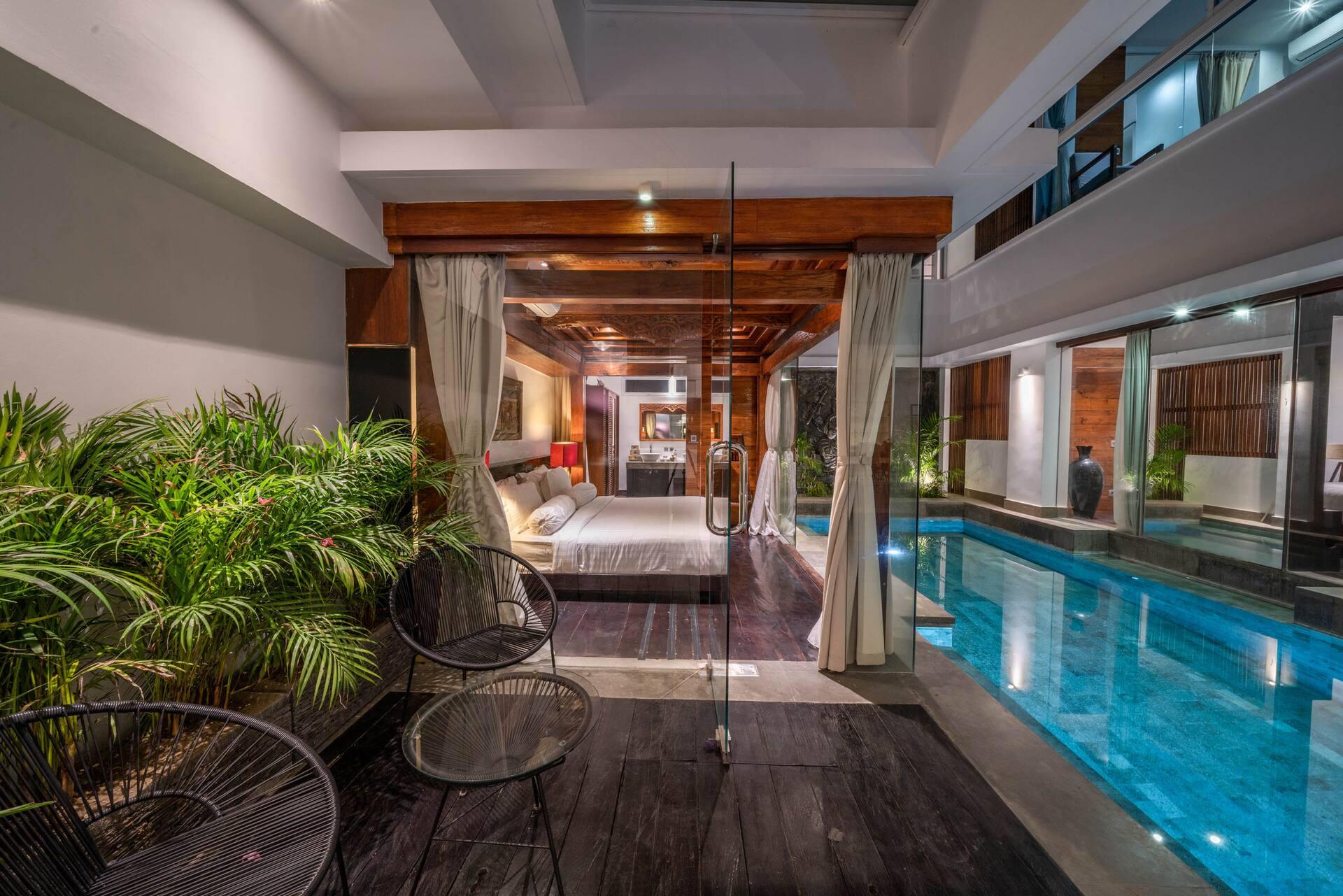 Loungers and curtained bedroom fronts along the pool terrace at Villa Tykhe