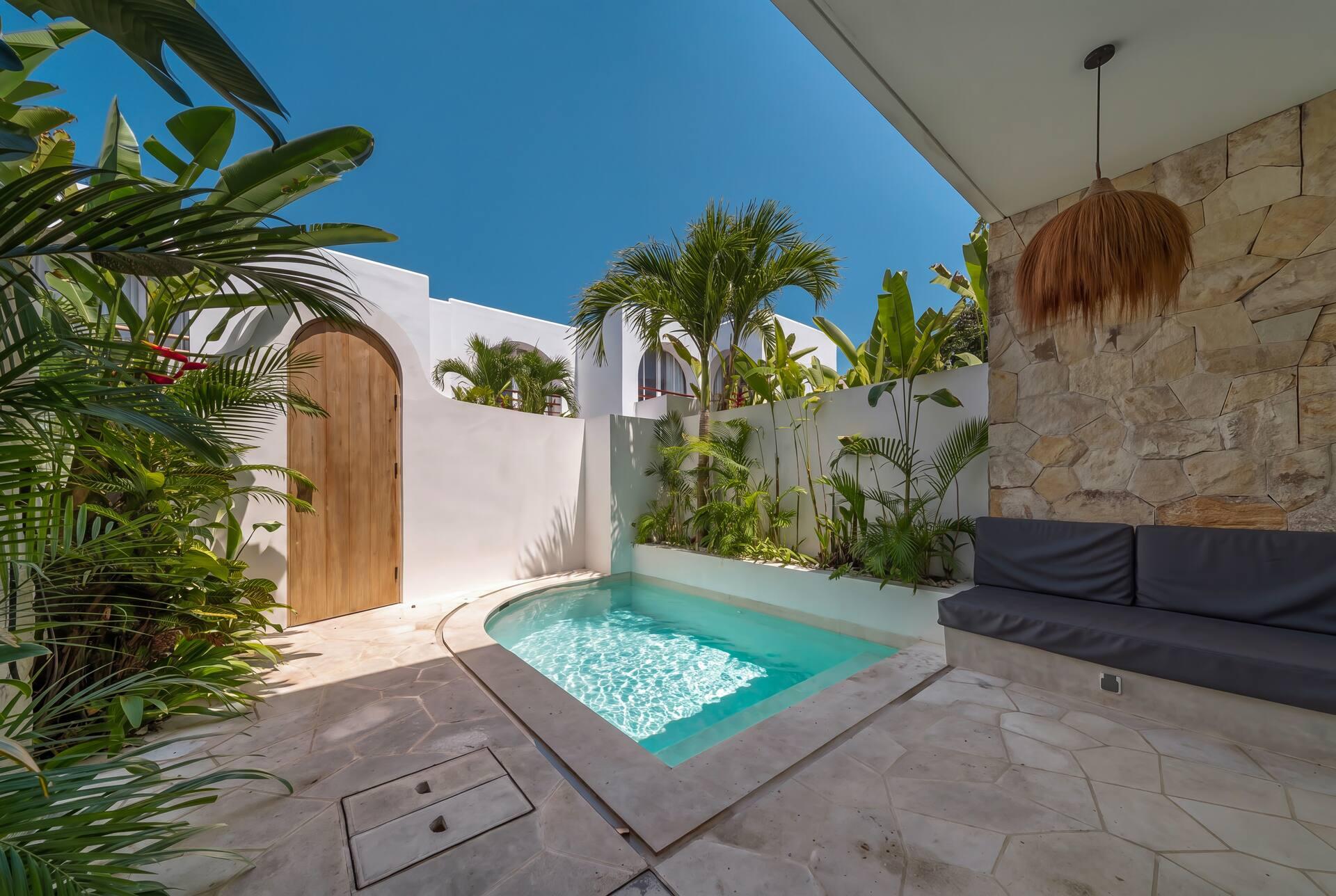 Arched timber gate, stone feature wall and a low daybed bench beside the courtyard pool