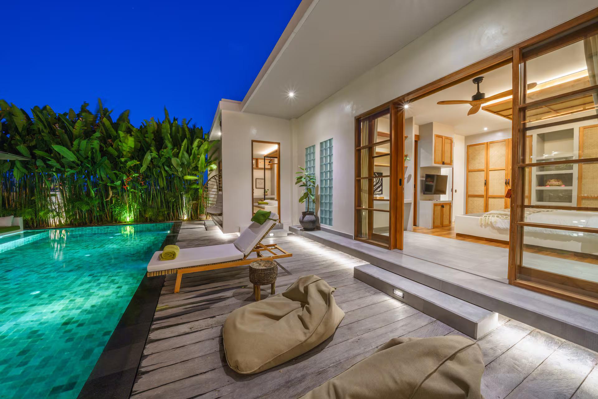 Timber pool deck with a beanbag and sun loungers, folding doors open along the house