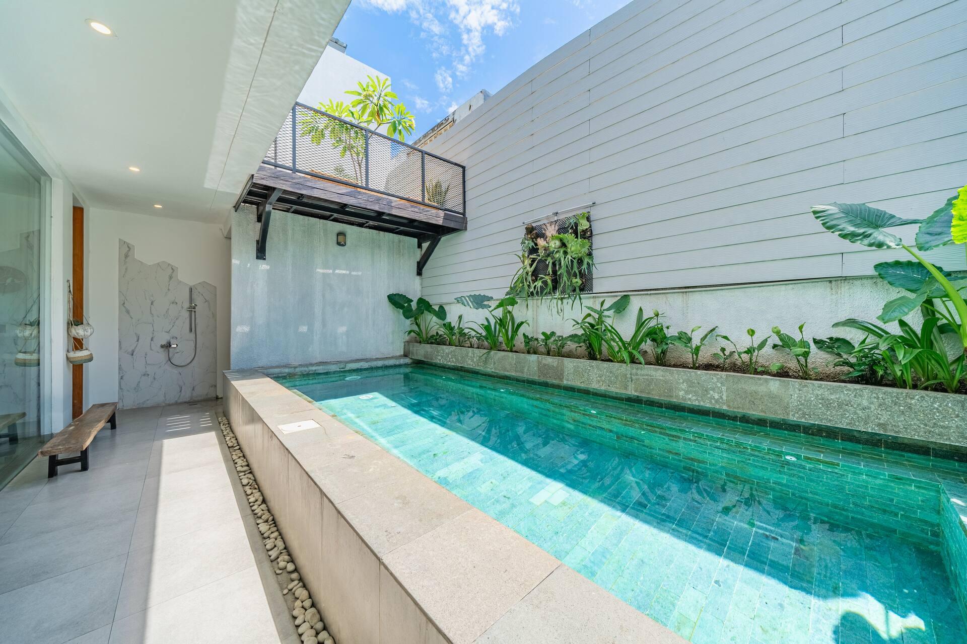 The pool from the far end, planting along the stone wall and the balcony walkway above