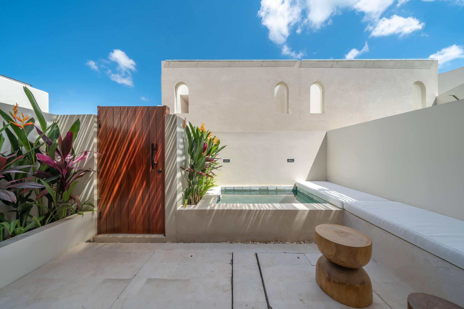 Walled pool courtyard with a built-in cushioned bench, timber stools and a slatted timber gate