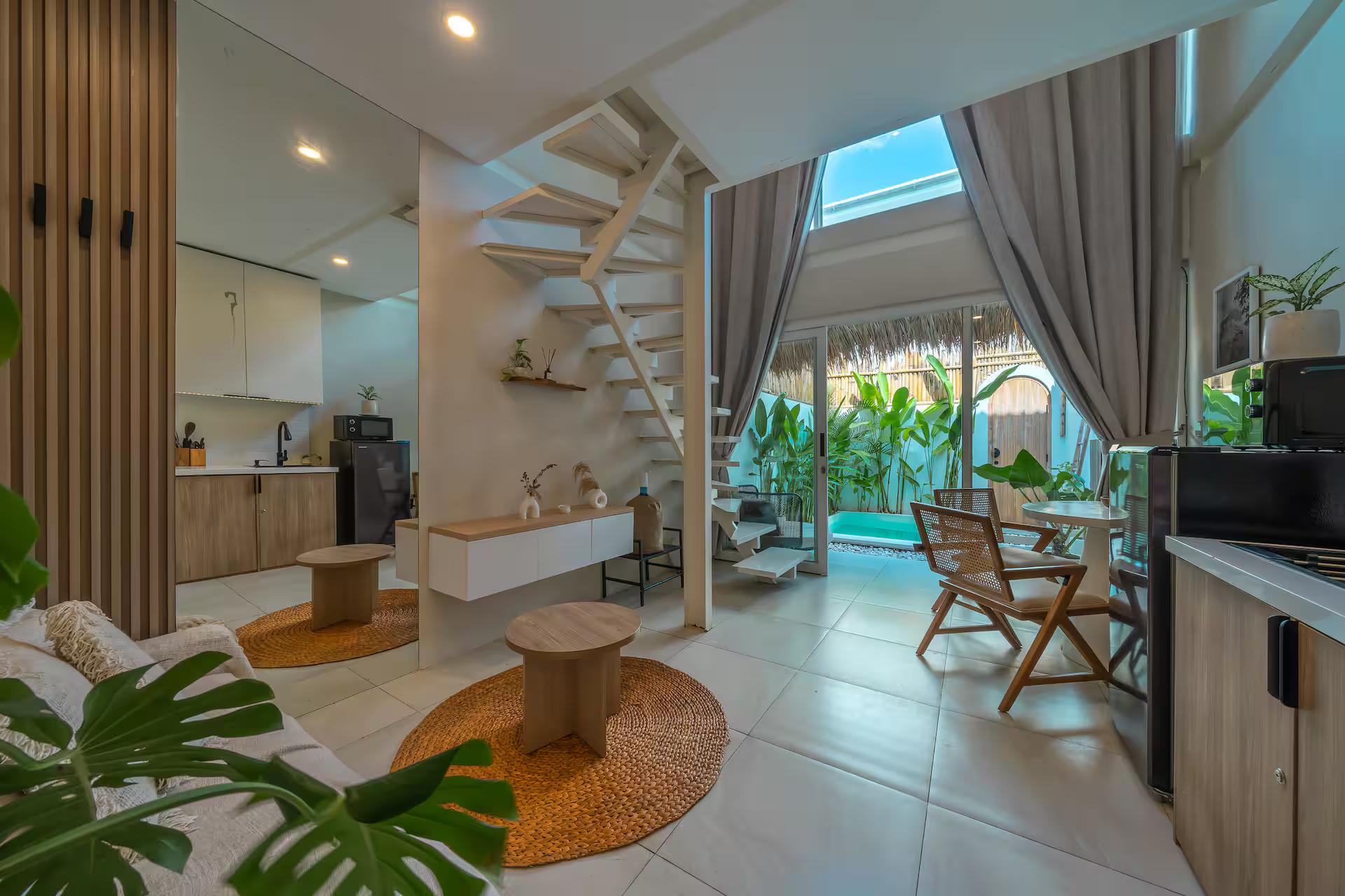 The galley kitchenette and white steel stair, glass doors open to the pool courtyard