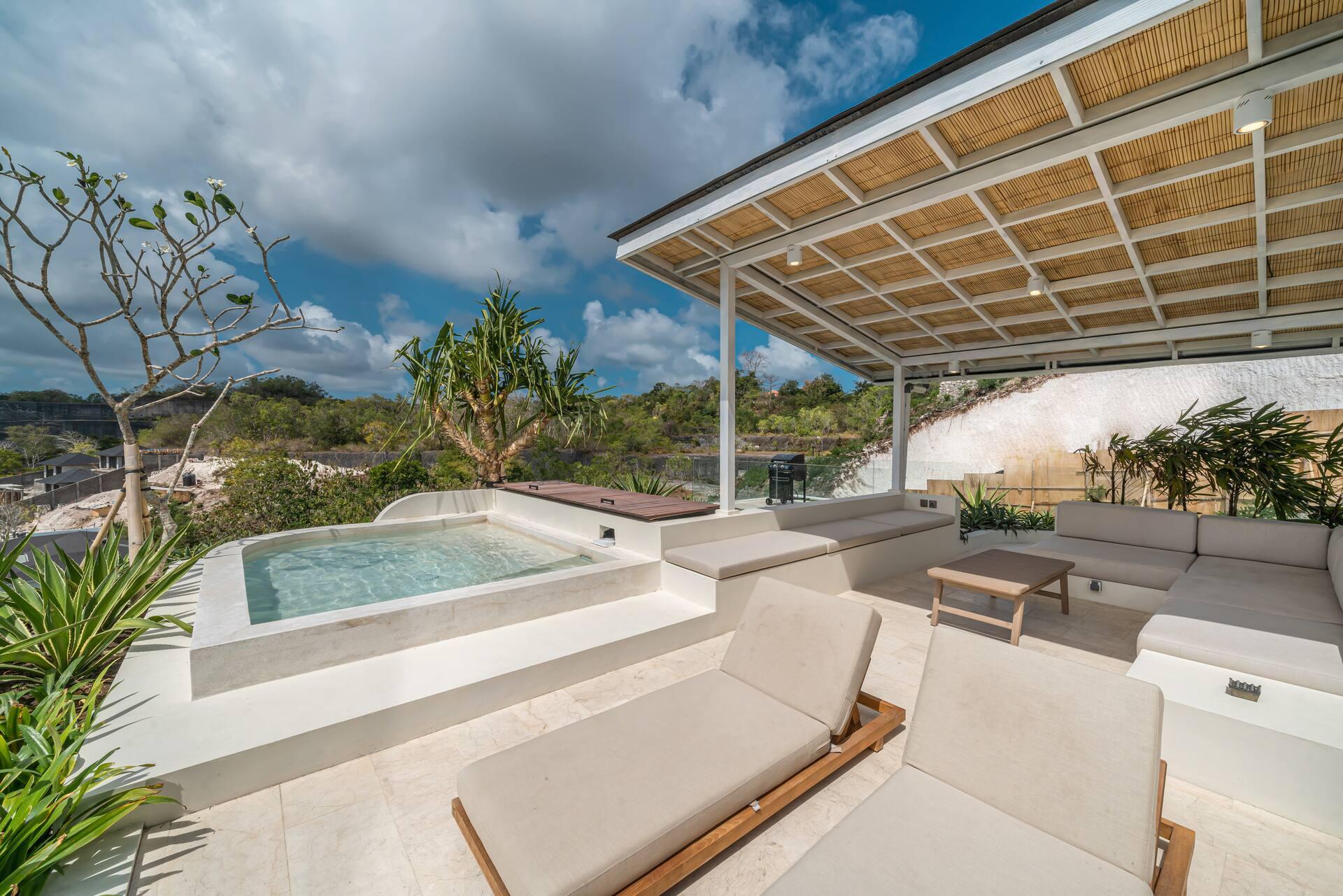 Rooftop plunge pool with built-in cream daybeds and timber loungers beneath a slatted pavilion