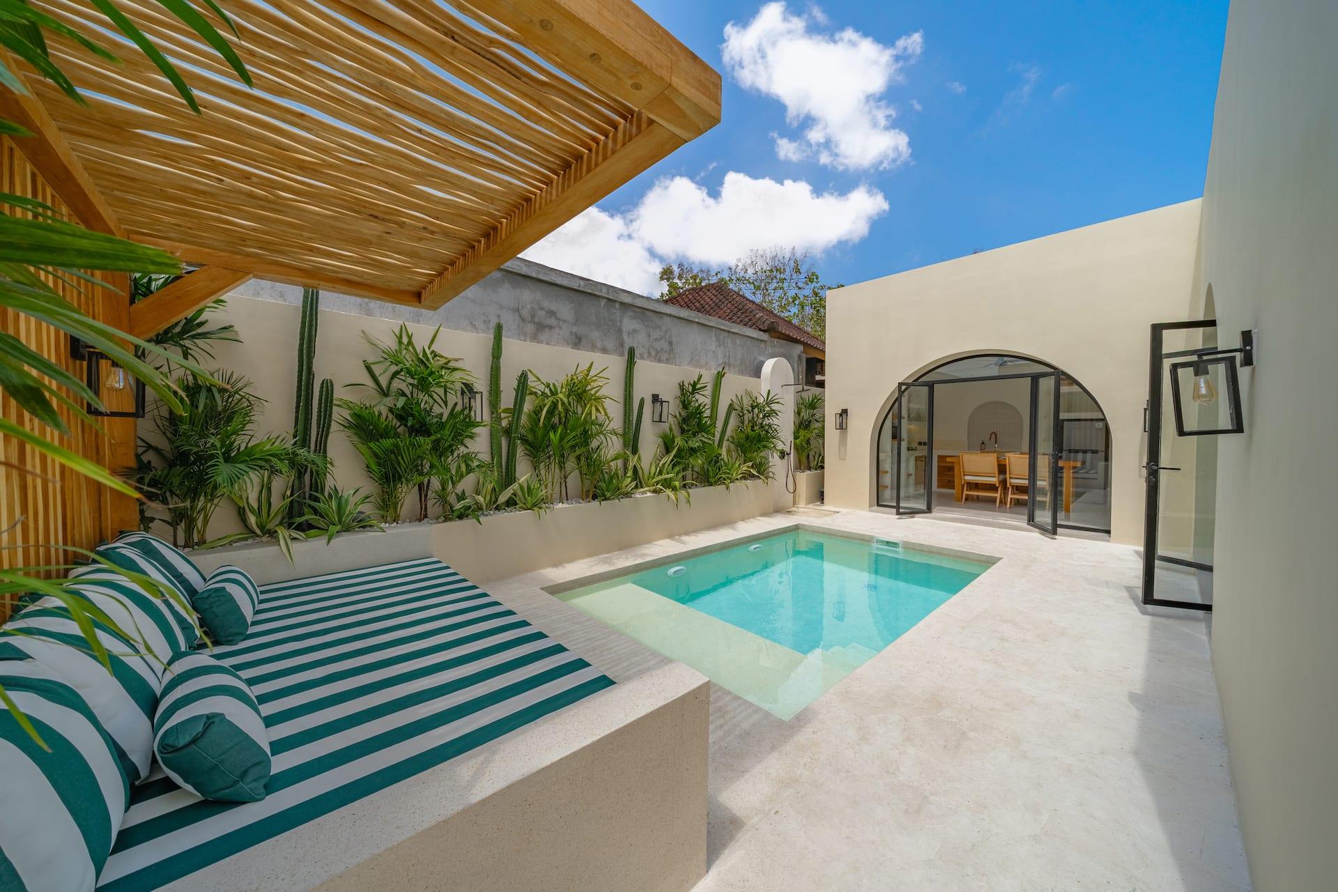 Shaded built-in lounge with green-and-white striped cushions beneath a slatted timber pergola