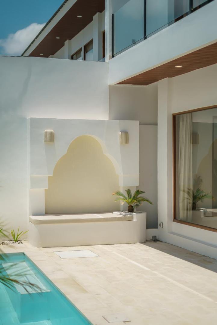 Pale-tiled lap pool running to a rendered arched alcove at the far end of the courtyard