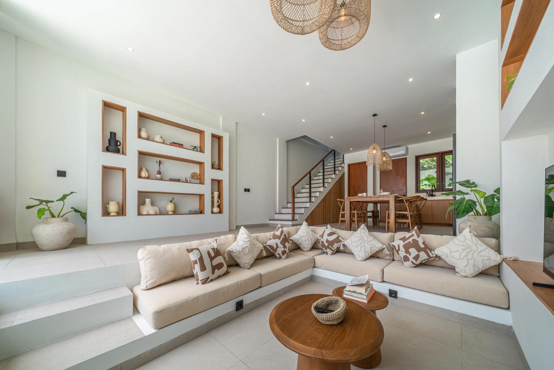 Built-in bench seating with cream cushions facing a wall of timber-lined display niches