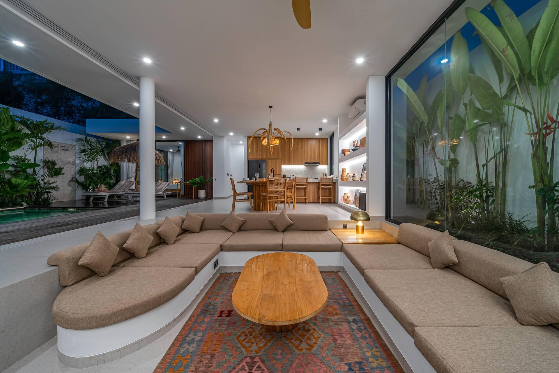 Sunken living room with a curved beige sectional around an oval timber slab table on a kilim