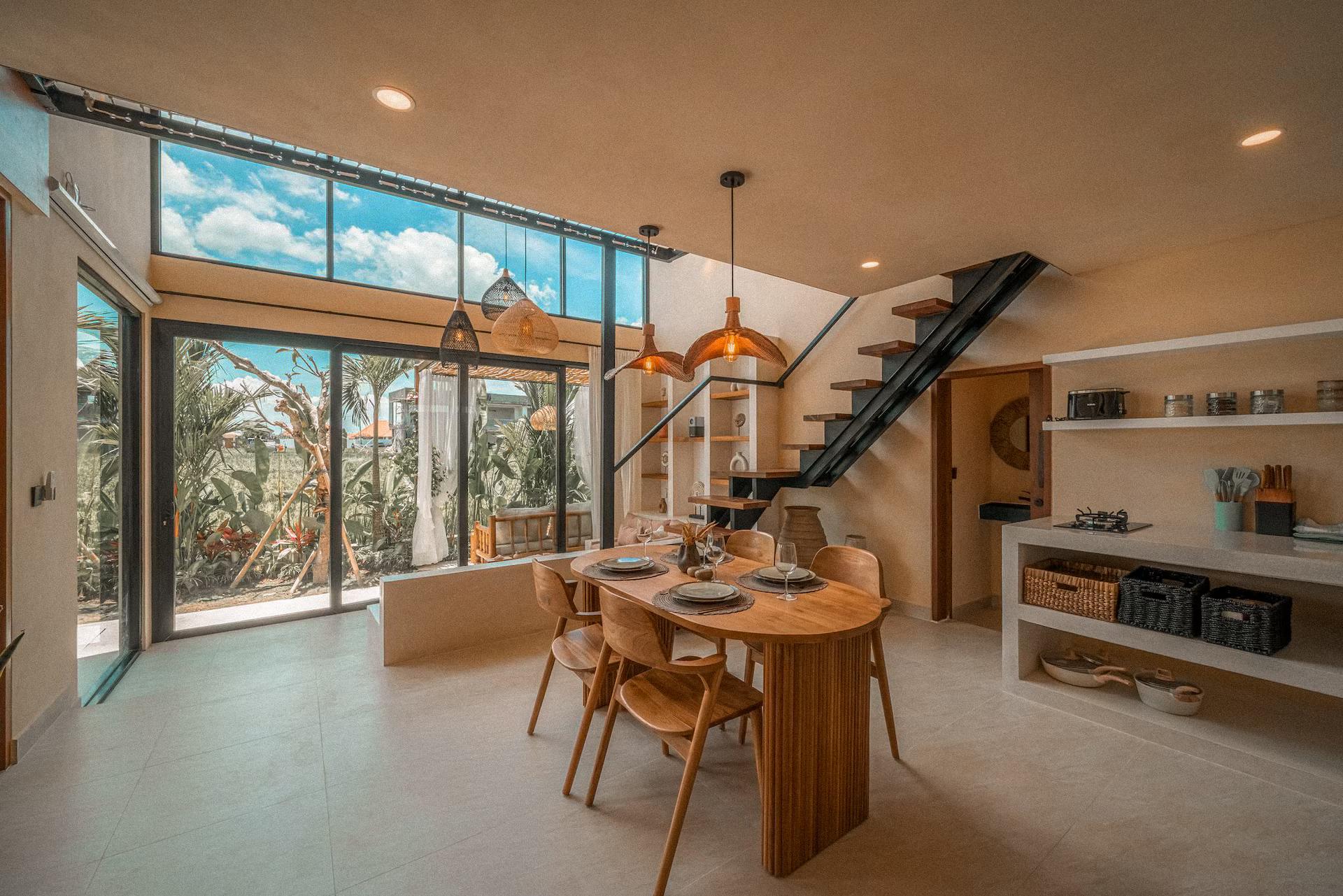 The double-height living room at Villa Ayo 1, glazing on two sides and the timber stair
