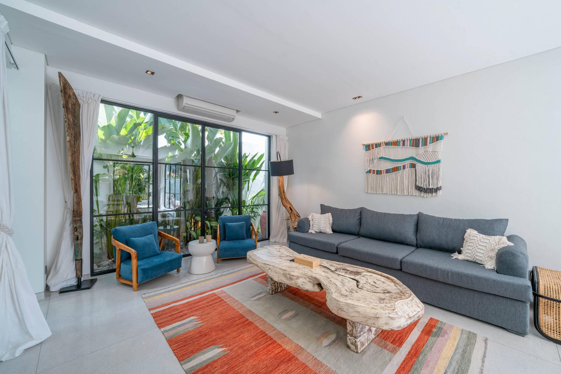 Living room with a grey sectional and a live-edge driftwood table on an orange kilim