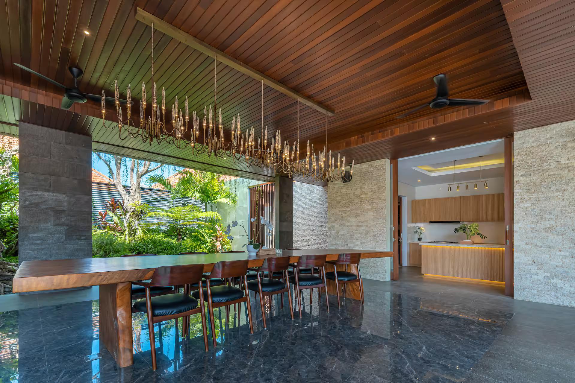 Dining table under a suspended bar of brass rods, slatted timber ceiling above