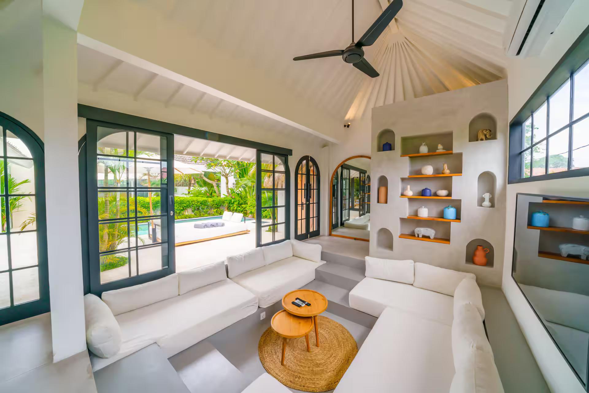 Sunken white lounge beneath a vaulted rafter ceiling, rattan drum tables on the lower floor