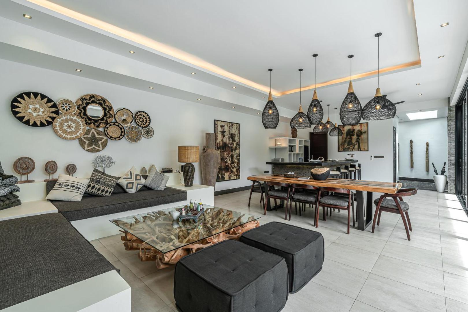 Open living pavilion at Villa Marlon, a white banquette beneath a wall of woven baskets