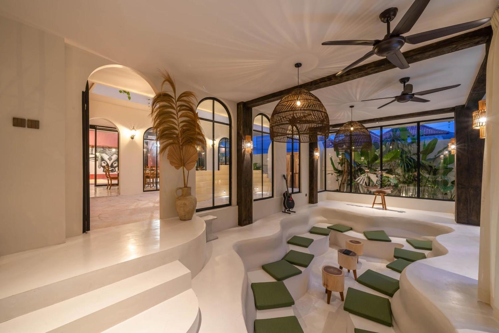Sunken pit of curved rendered banquettes with olive cushions, open to the courtyard