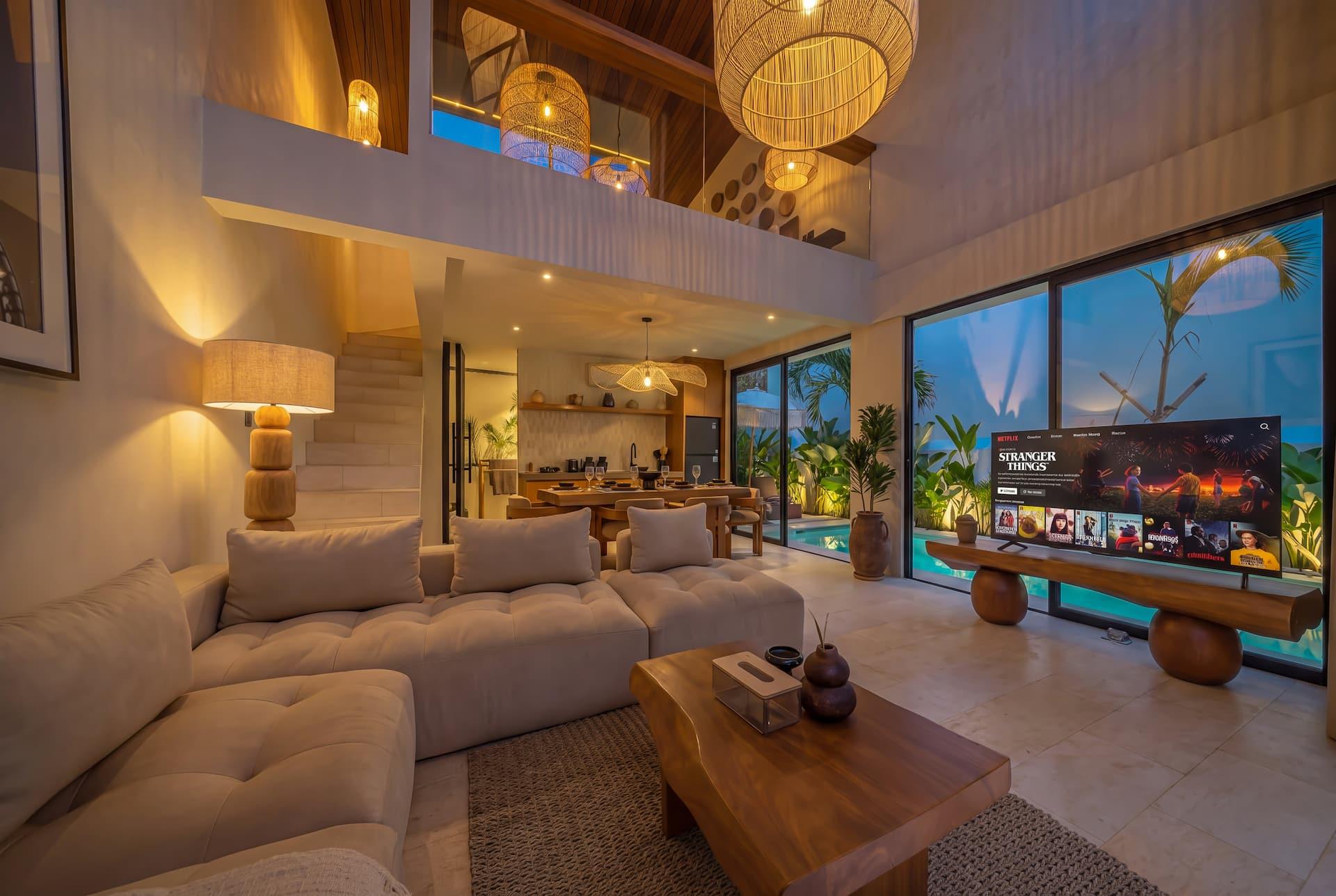 Double-height living room at Villa Elementa with a deep sectional sofa, Smart TV and mezzanine above