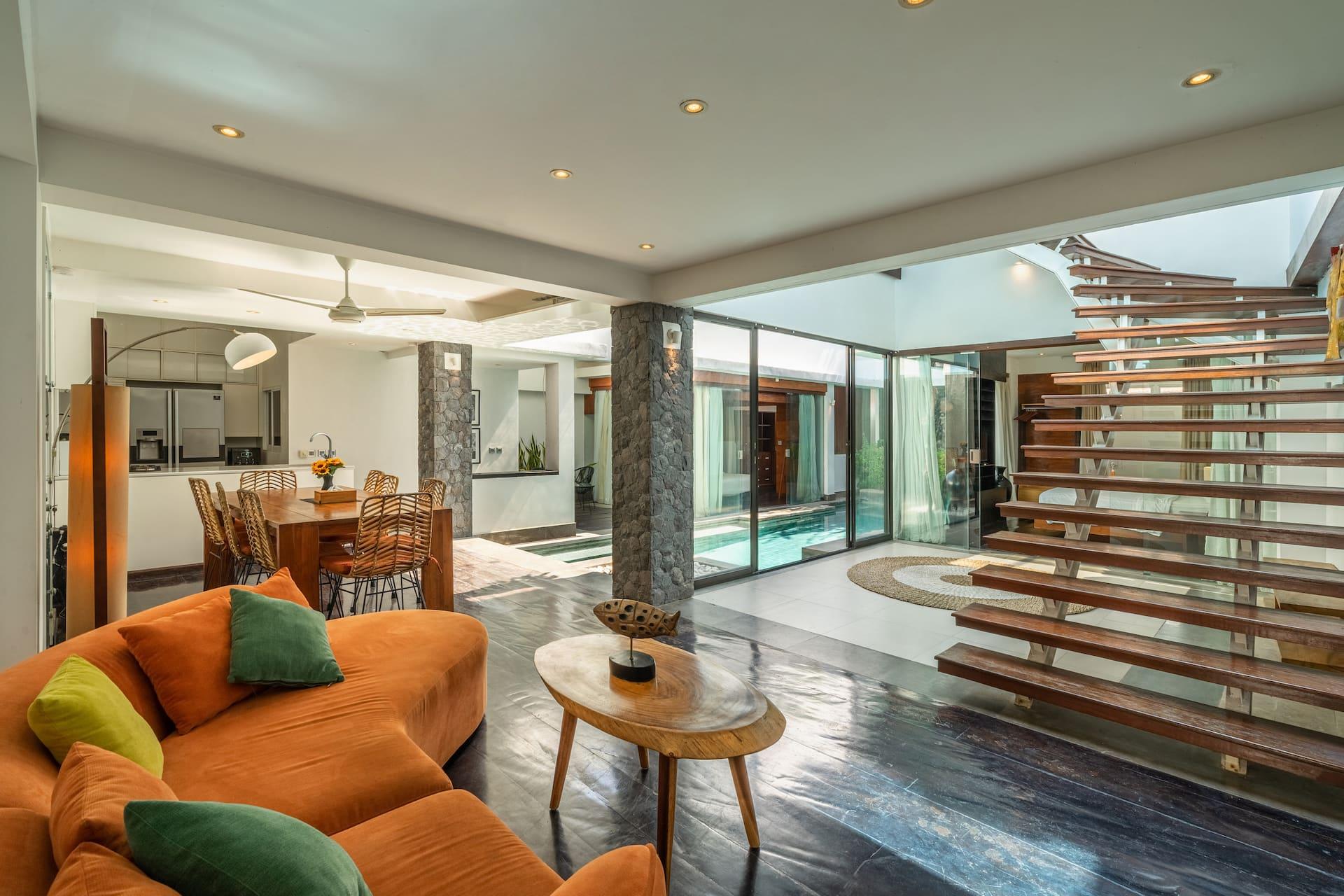 Open-plan living and dining at Villa Tykhe with a curved sofa and the pool alongside