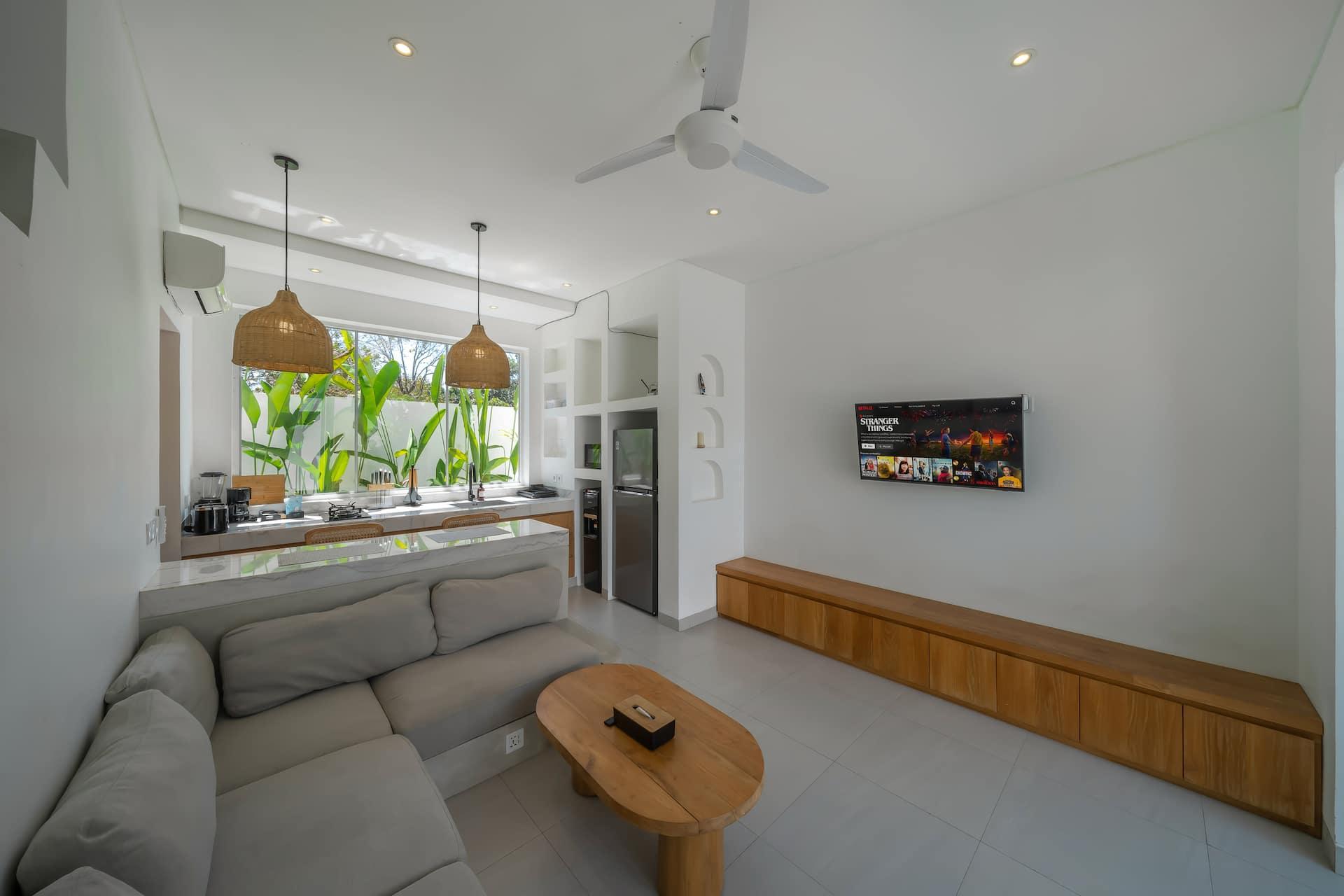 Open-plan living at Las Casas 5, with a linen sofa, built-in timber bench and rattan pendants