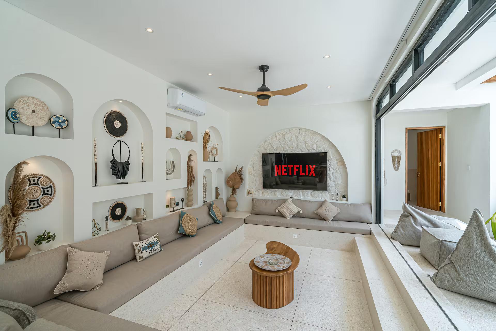 Sunken living room with a wall of arched niches and a seventy-five-inch screen
